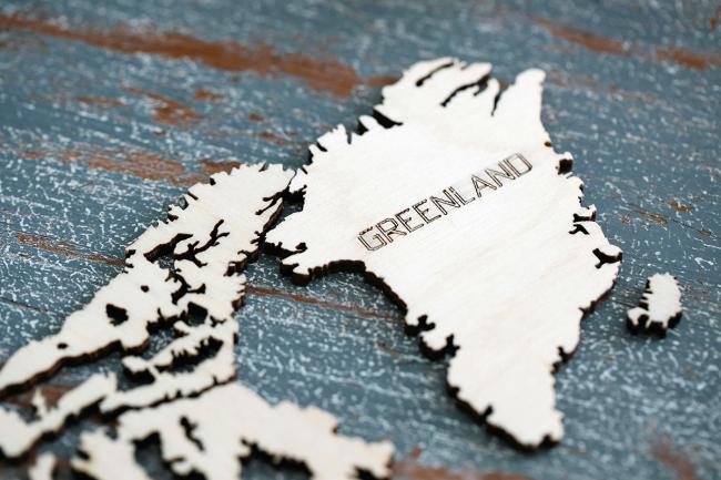 A wooden map of Greenland, displaying it off the coast of North America.