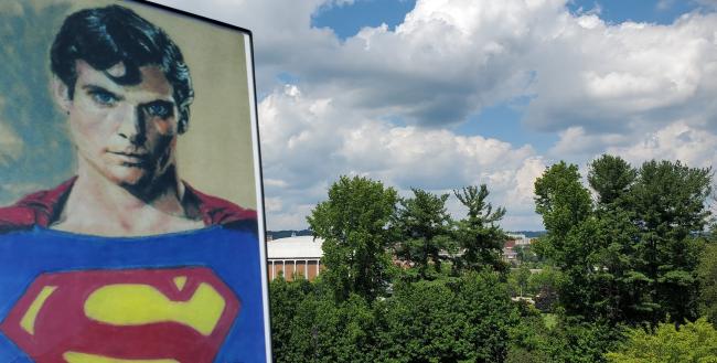 An artistic image of Superman is shown against the Athens skyline, which includes the Convocation Center