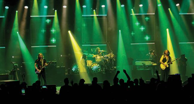  members of the band My Morning Jacket perform on stage surrounded by green and yellow lighting