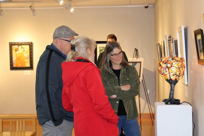 Three people look at a hand-crafted lamp in the art gallery at OHIO Chillicothe