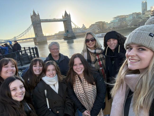 a group of 11 students and faculty members (total) in front of the Tower Bridge in London