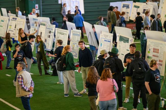 OHIO students stand  in front of their research posters and discuss their work at the Student Research Expo in Walter Fieldhouse