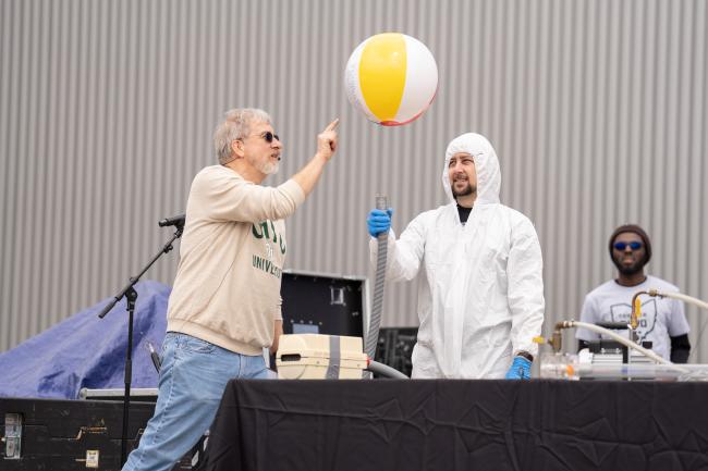 An OHIO faculty member pokes at a beach ball as part of an science exhibit,  while two other OHIO representatives look on  at the Science Day event