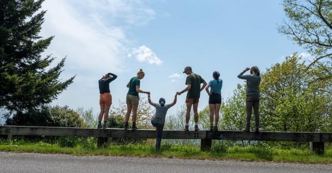 OHIO students stand  together outside on a warm summer day while looking out across a valley