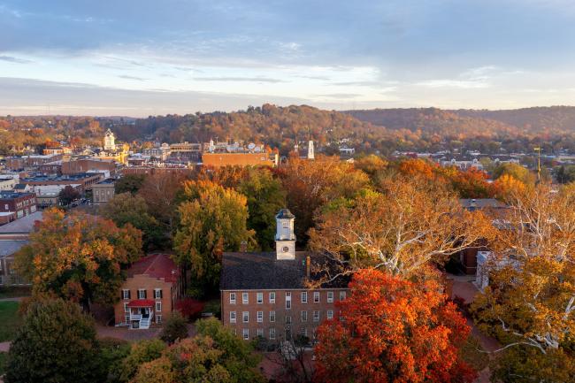 Cutler Hall is shown surrounded by colorful trees, with hilldsides in the background in this aerial image
