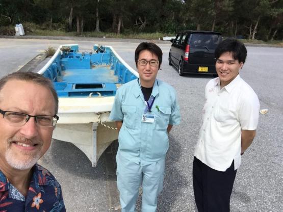 Thompson takes a selfie with Yonashiro and Nakada, with the washed up boat behind them in a parking lot