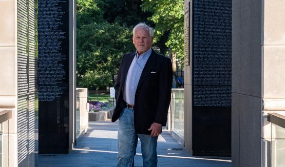  Ohio University graduate P. Joseph “Joe” Mullins, MFA ’78, stands among the names of the more than 10,000 West Virginians who served and died in the first four wars of the 20th century and whose sacrifice is memorialized in the West Virginia Veterans Memorial he designed.&quot; loading=&quot;lazy 