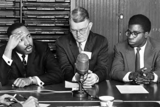  This image appears in the Ohio Alumnus, January 1960, captioned: &quot;Each day while the Conference was in session, a press conference was held each morning with newsmen and photographers from newspapers, radio and television attending. Above Martin Luther King answers a question for the newsmen. Seated beside Rev. King is Dr. Winburn Thomas, leader of the forum on racial tensions. Mr. &#039;Bola Ige, co-secretary of the conference, which is sponsored by the National Student Christian Federation, in on the right.&quot; (