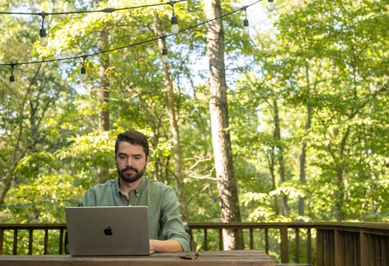  An OHIO student works on a computer while sitting outside 