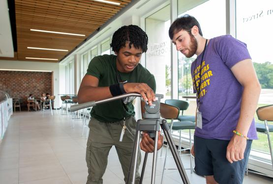  An instructor and participant set up camera equipment at the 2023 High School Media Workshop 
