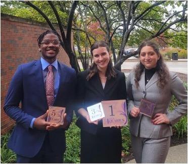 Three speech and debate team members pose with their awards