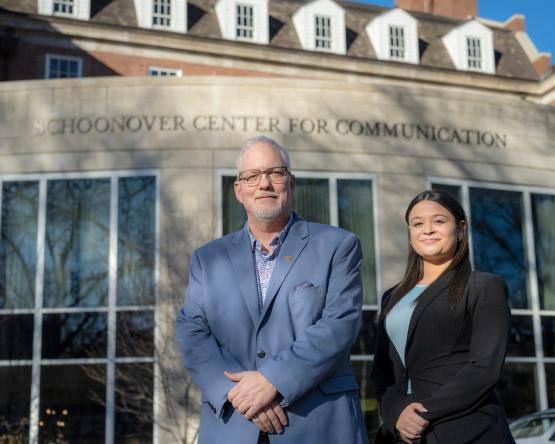 Dean Scott Titsworth poses with sophomore Bella Moyers-Chavez in front of the Schoonover Center for Communication