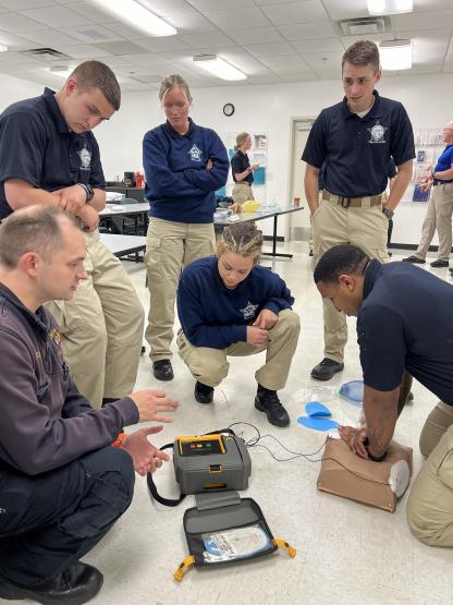 Chris Green Jr. practices skills with the automated external defibrillator while classmates observe