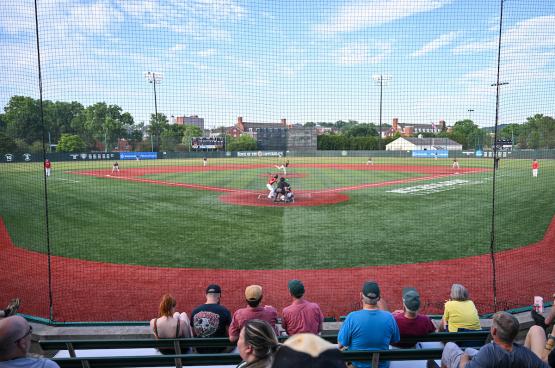  Wide shot of a baseball diamond taken from the bleachers behind home base, with spectators watching the game in the foreground 