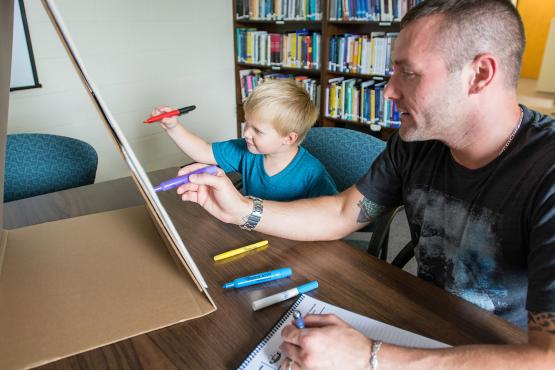 An arts therapist sharing an eisle with a young patient. 