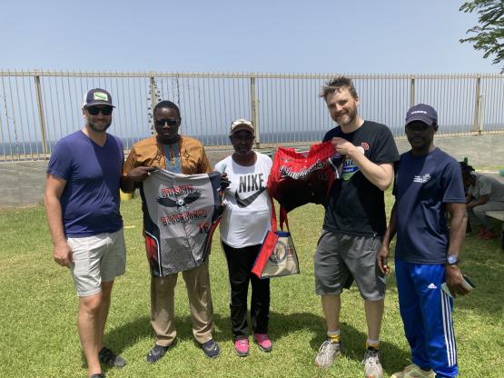 A group of people pose on a baseball field, holding up jerseys