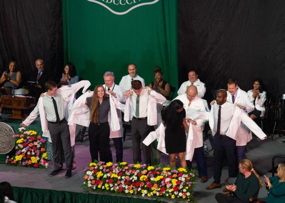 Students put on white coats at convocation