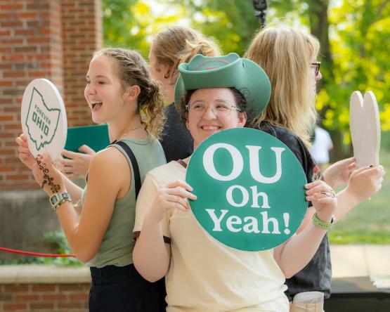 Students stand wearing OHIO gear and holding a sign that says "OU oh yeah!" at Welcome Week 2024