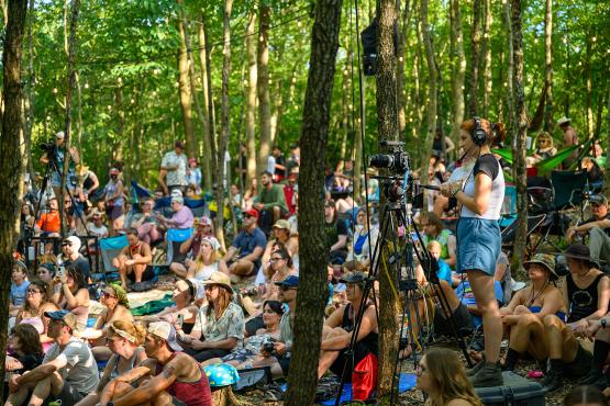  An Ohio University student operates a camera filming the Creekside Stage at the Nelsonville Music Festival with the audience behind. 