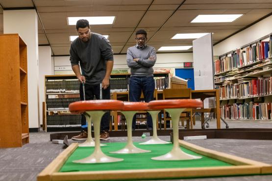 Tylor Brooks plays miniature golf in Alden Library while his father, Jeff Brooks, watches during Dads Weekend 2023.