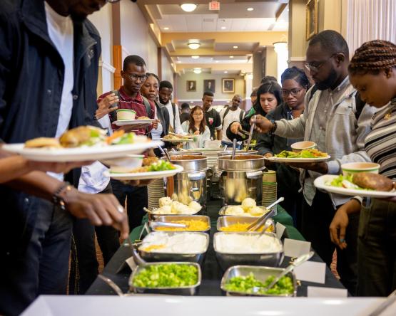 OHIO community members get food from a long table at the International Dinner in the Baker University Center