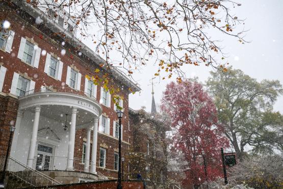 Ellis Hall is surrounded by colorful trees while snow falls on OHIO&amp;#039;s College Green