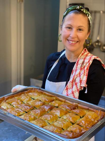 chef christina xenos holds a tray of spanakopita