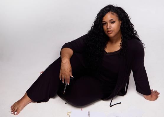  Hadiya Ray, seated on the floor with journals spread out in front of her 