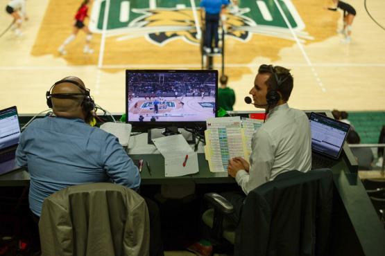  Two announcers face each other in the stands overlooking the OHIO basketball court 