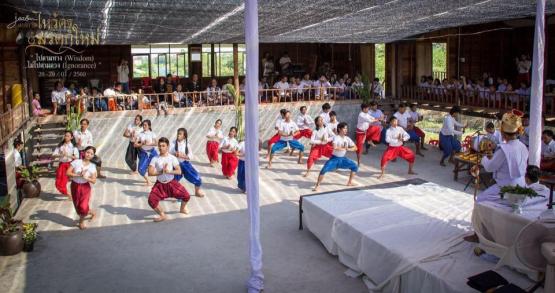  Thai Moradokmai Theatre dancers are shown dancing in a large group 