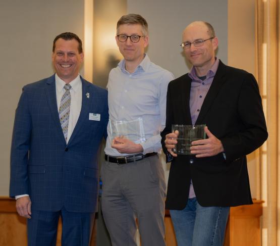 Eric Muth, Matthew Cornish and Ingo Trauschweiser are shown on stage at the awards ceremony