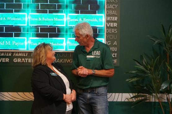  Amy Toth speaks to another individual while standing in front of the Legacy Wall in the Walter Center 