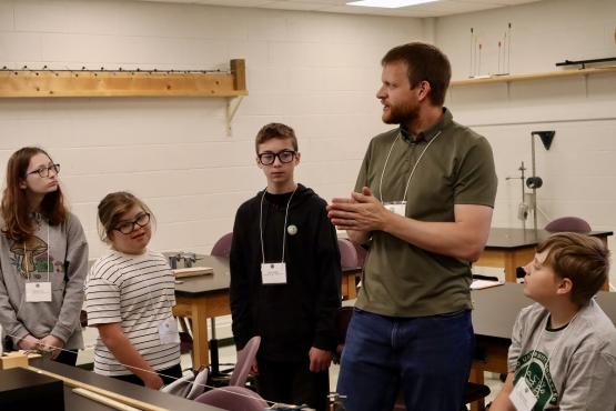 A teacher talks with a group of middle school students in a classroom at the STEM Discovery Day event