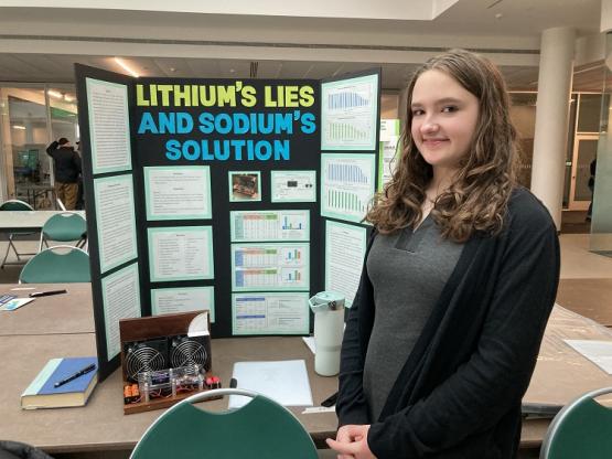 Emile Wright is shown in front of the poster for her project on Lithium's Lies and Sodium Solution