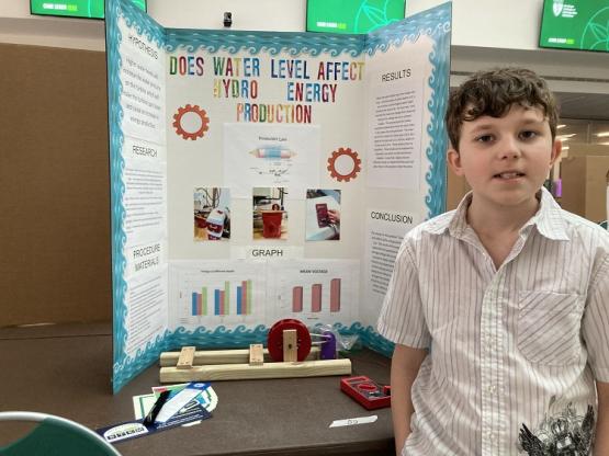 Ian Flemming is shown in front of the poster for his project on Does Water Level Affect Hydro Energy Production