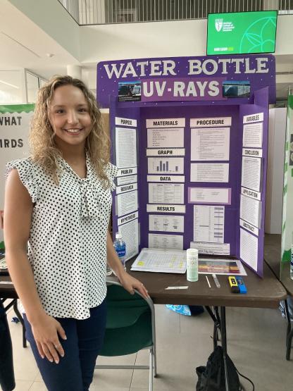 Allison Payton is shown in front of the poster for her project on Water Bottles and UV Rays