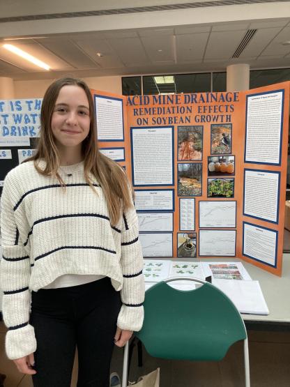 Norah House is shown in front of the poster for her project Acid Mine Drainage Remediation Effects on Soybean Growth