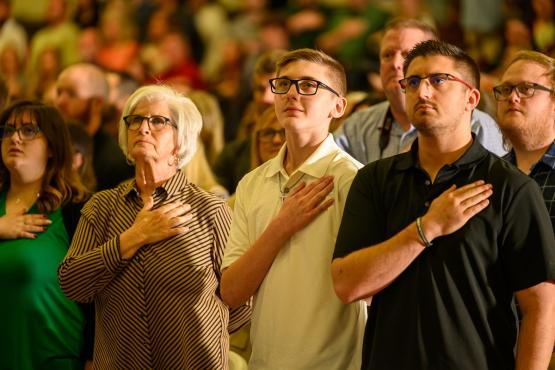 Family members and friends hold their hands over their hearts during the OHIO Lancaster Graduation Recognition Ceremony