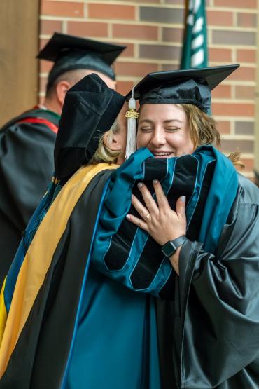 An OHIO faculty member hugs a graduate on the stage at the OHIO Southern Graduation Recognition Ceremony