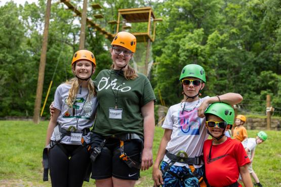  Participants at Cat Camp smile together for a photo outside while wearing helmets for the ropes course 