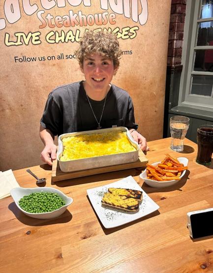 Jack Legath is shown with a table full of food items before a challenge at a steakhouse