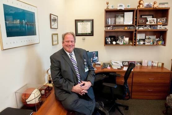  Retired HCOM Admissions Dean John Schriner leans against a desk 