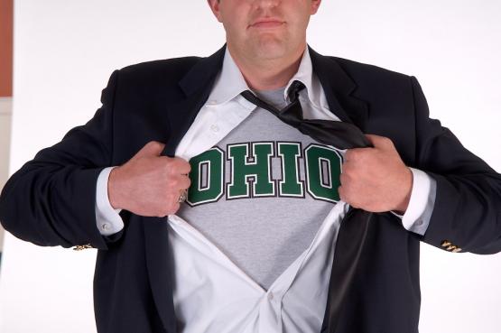 An individual opens his shirt as Superman does in movies and reveals a shirt with an OHIO logo