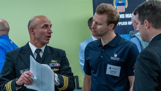 Three individuals are shown talking at an APEX Accelerator event
