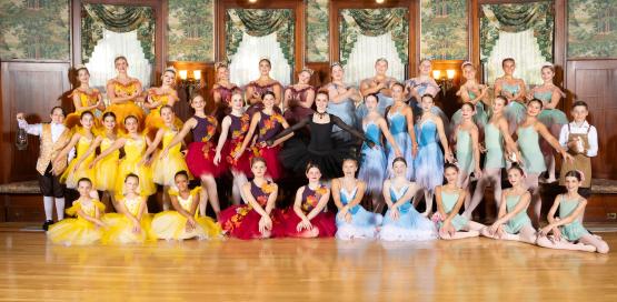  Approximately 50 young ballet dancers in full brightly colored costumes smiling 