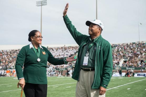  President Emeritus Roderick J. McDavis and First Lady Emerita Deborah McDavis wave to the crowd at a Homecoming football game in Peden Stadium 
