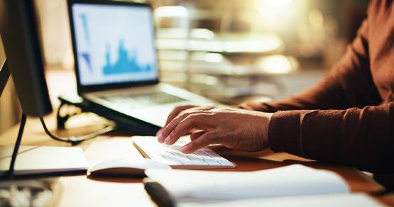 A person wearing a brown sweater sits at a computer monitor