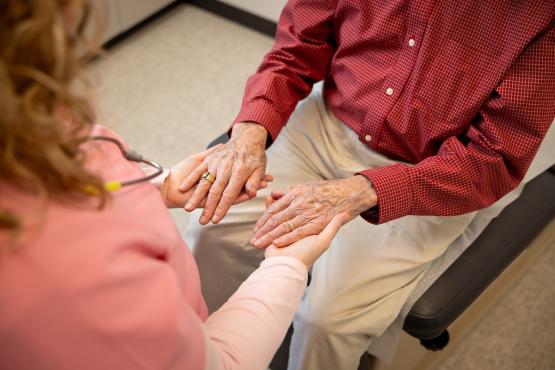 A clinician looks at the hands of an older patient