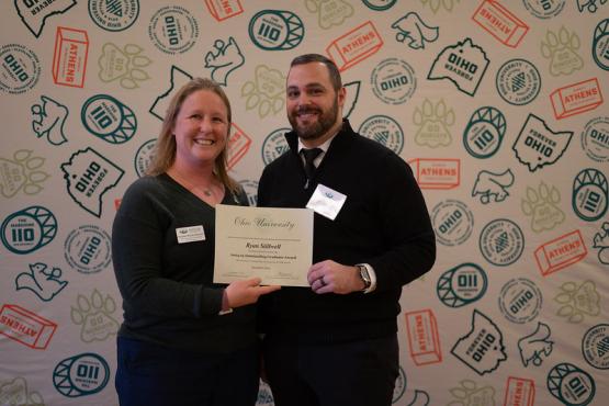 Natalie Kruse Daniels and Ryan Stillwell hold the Outstanding Graduate Award that Stillwell won