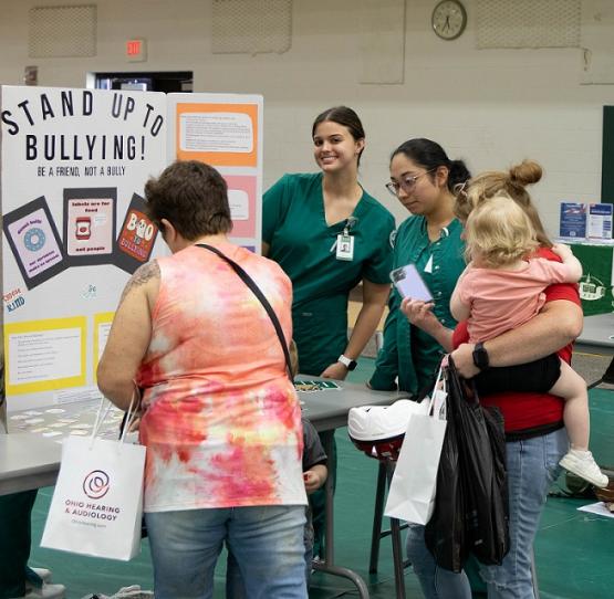 two nursing students talk share information on stopping bullying at a health fair